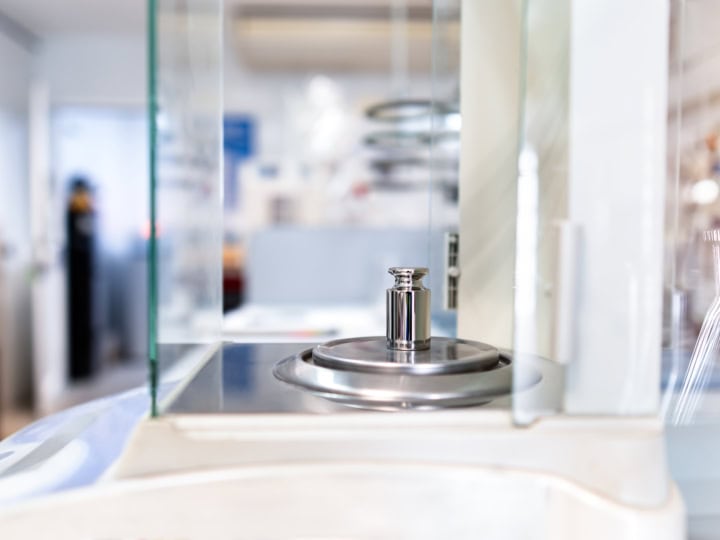 Über uns 1 Nahaufnahme eines Metallgewichts zur Kalibrierung auf einer Waage im Labor.